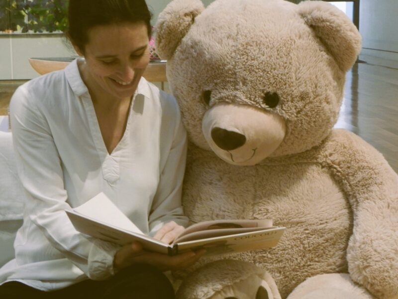 La formatrice lit une histoire à un énorme ours en peluche
